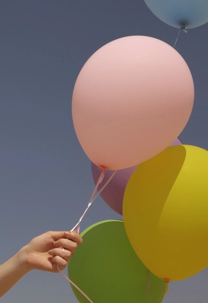 photo of hand holding balloons